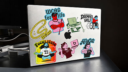 Zilverkleurige laptop met zeven kleurrijke stickers over digitale toegankelijkheid: een gouden ketting met ‘WCAG’, een persoon met taststok bij ‘WCAG for life’, een lopende laptop met taststok, een rolstoelgebruiker bij ‘OpenGemeenten Drempelvrij’, een mediterende persoon bij ‘Focus state’, een persoon met een roze laptop en een bokser bij ‘A11yCat’.